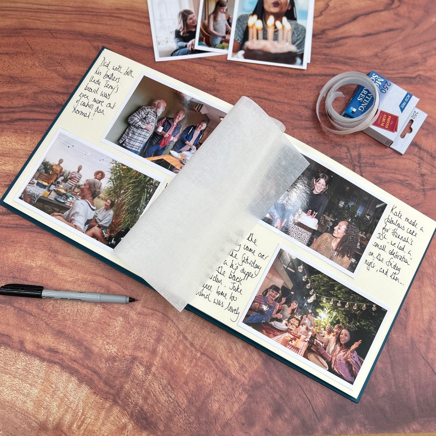a photo album lies open on a coffee table and you can see all the photos inside. Next to the photos are handwritten messages. Also on the table is a pile of spare photos and a box of mounting squares