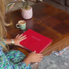 a woman picks up a large red wedding guest book and flicks through the pages. She also strokes the front of the book
