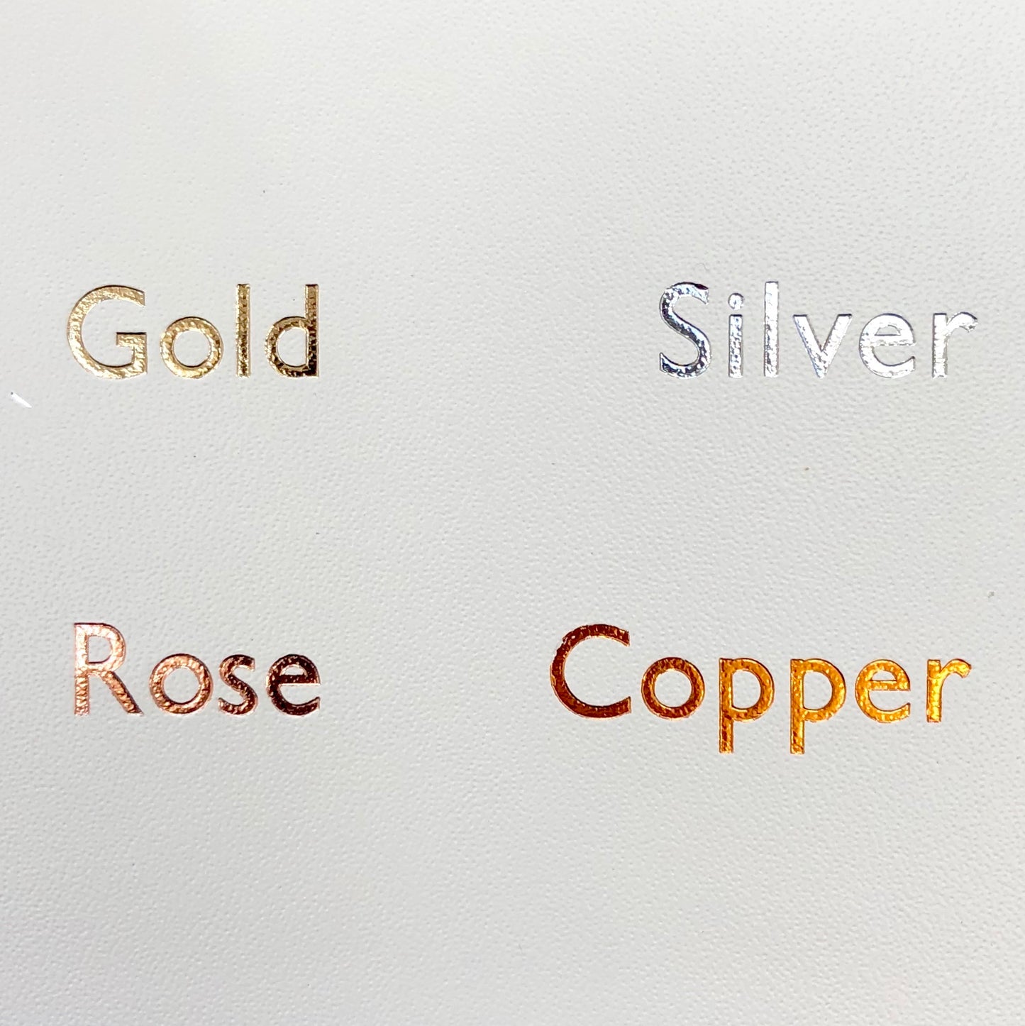 on a piece of white leather you can see the different colour foils with which you can print your wedding guest boo - gold, silver, rose gold and copper