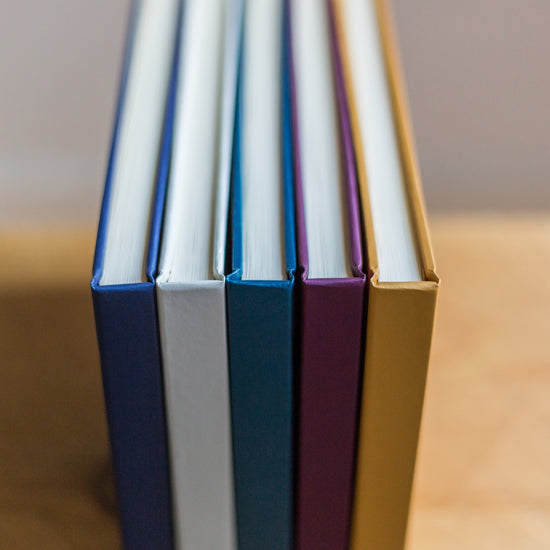 five wedding guest books are in a rown so you can see the different colours available 