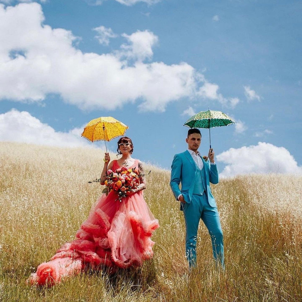 Colourful bride and groom in a corn field holding parasols