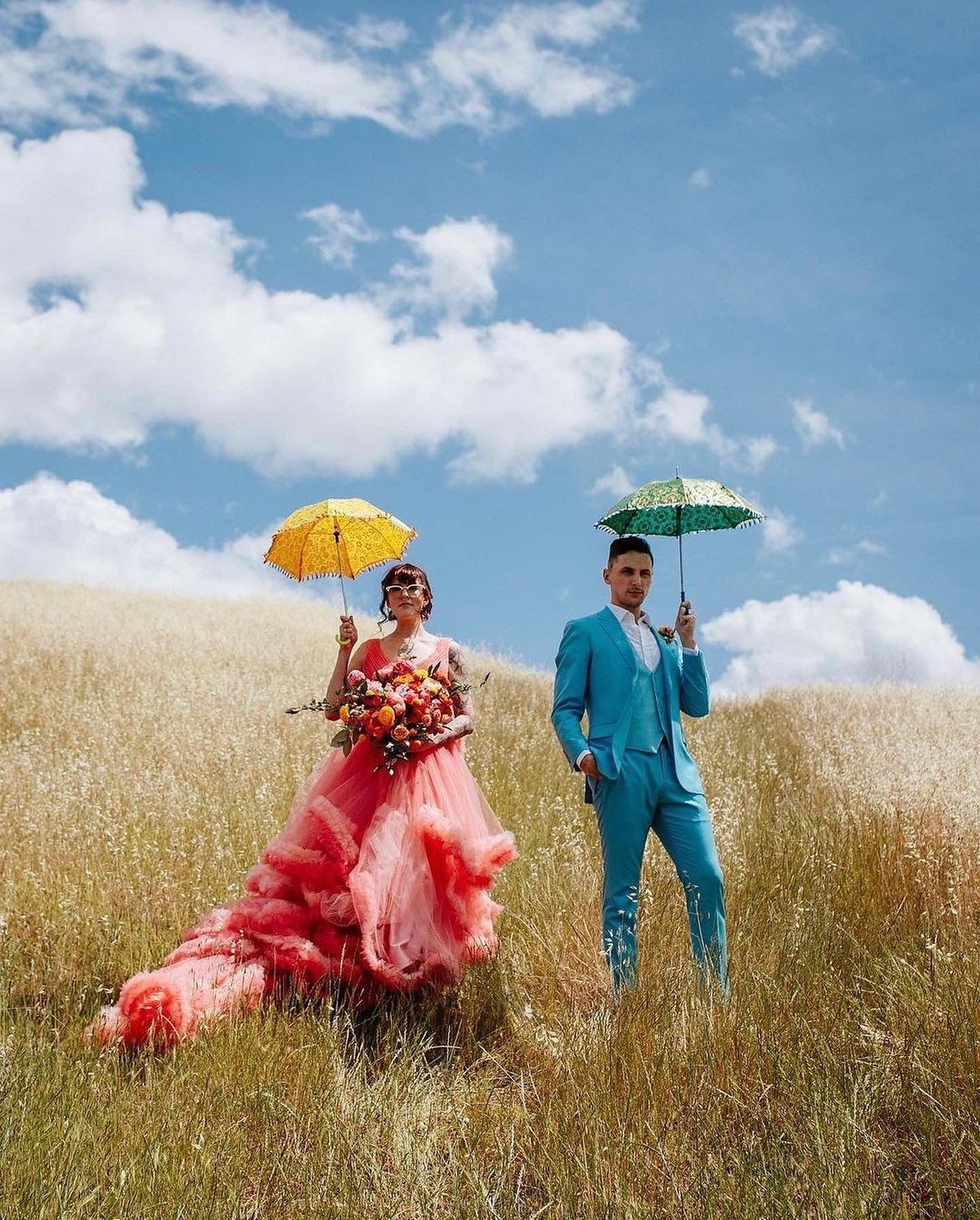 Colourful bride and groom in a corn field holding parasols