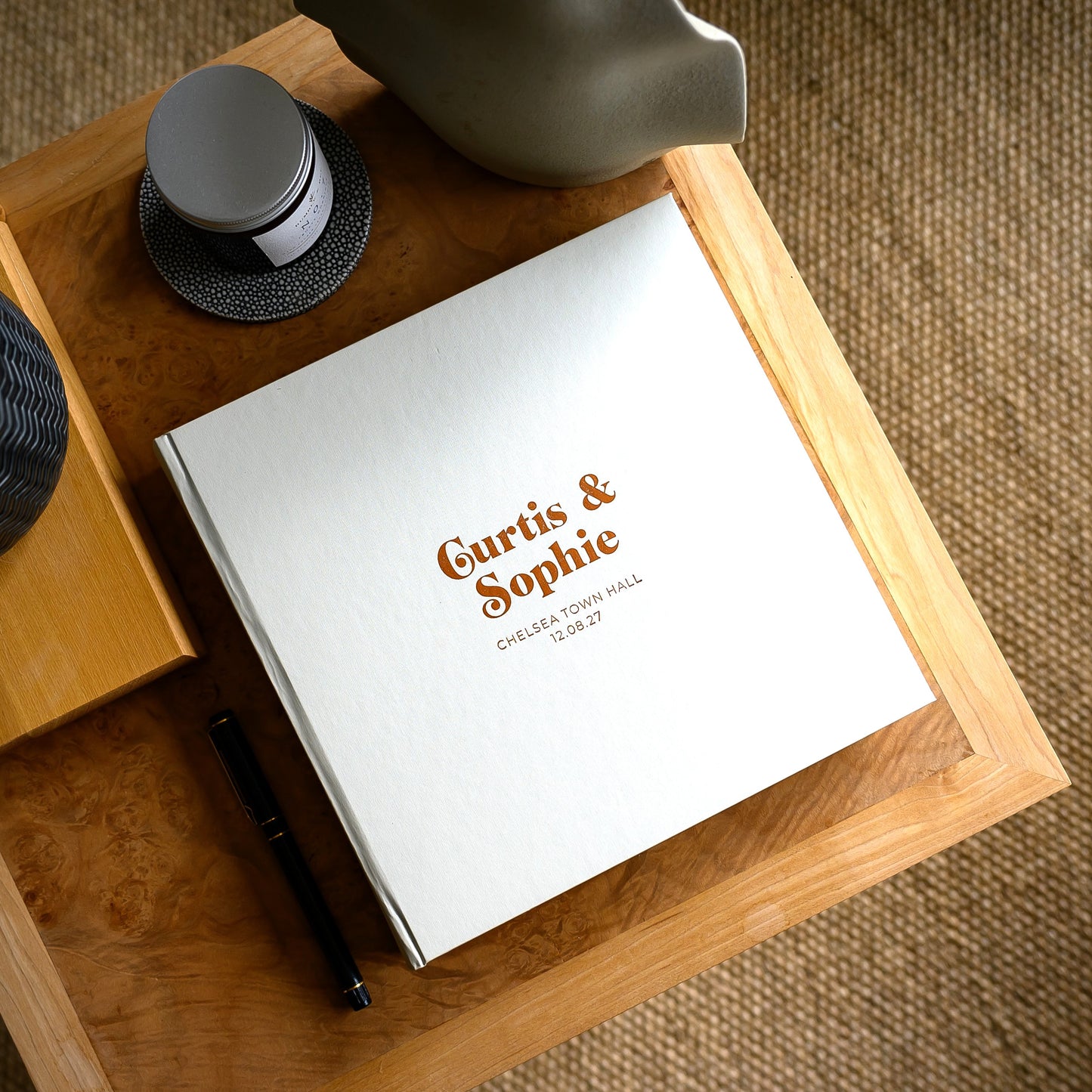 Pearl-coloured hardback wedding guest, personalised with two names, on a coffee table