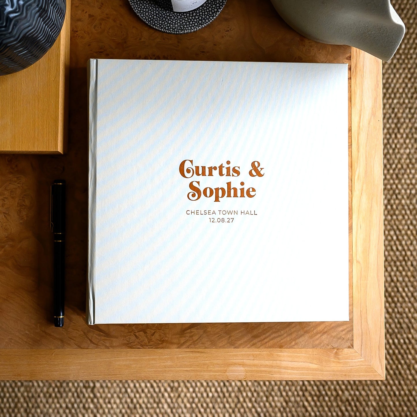 Pearl-coloured hardback wedding guest, personalised with two names, on a coffee table