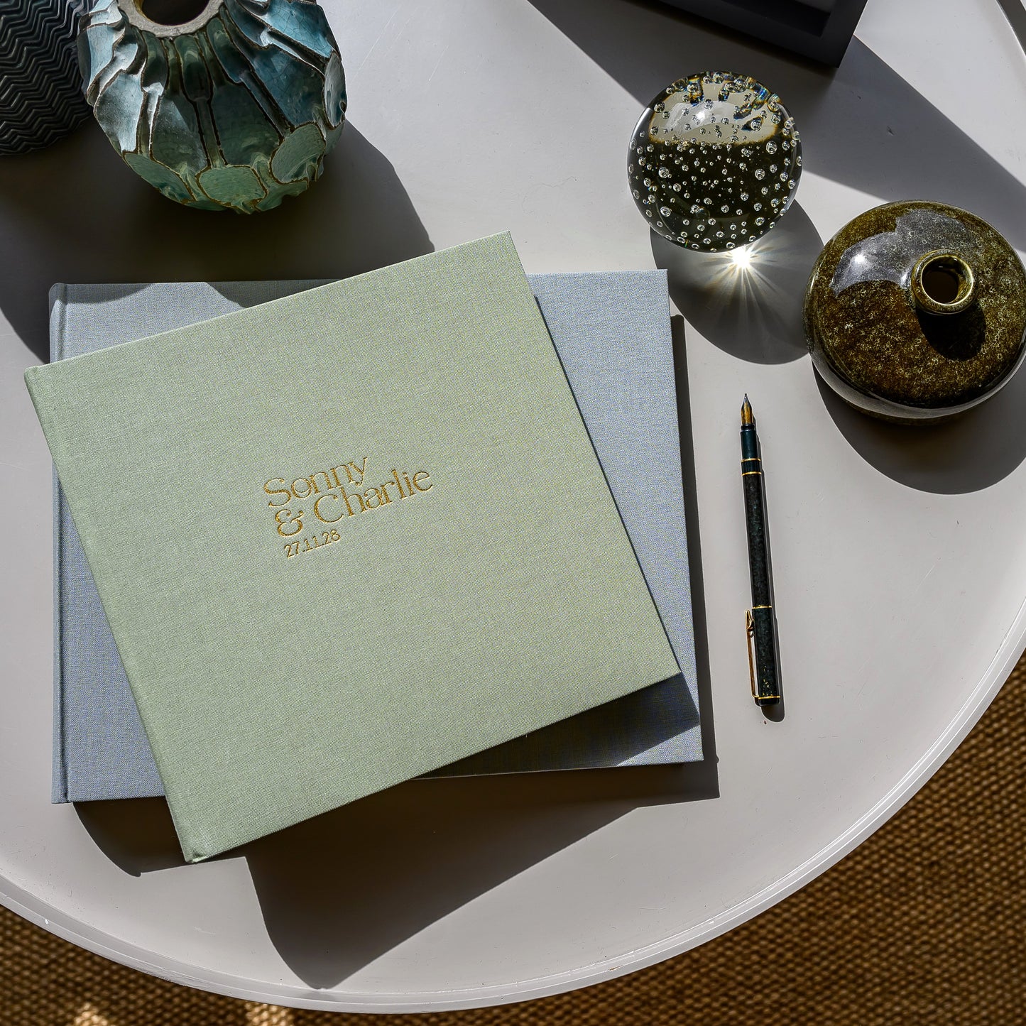 Woman holding a pale green wedding guest book personalised with the printed names 'Sophie & Charlie' on the front.