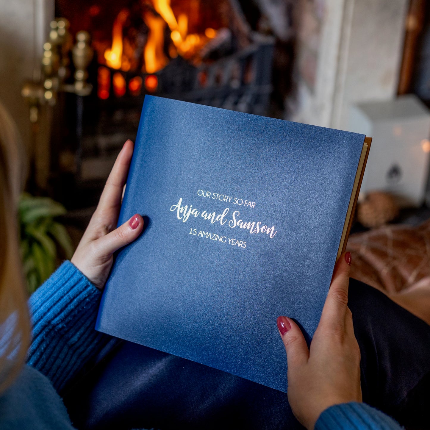 A woman is holding a photo album allowing us to see the personalisation on the front of the book. 