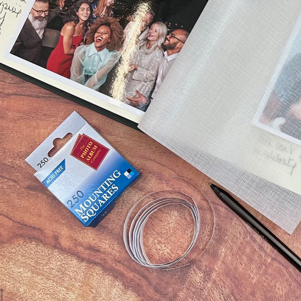 
                      
                        There are mounting squares ready to be used. There is part of an album also visible and a pen for writing down memories.
                      
                    