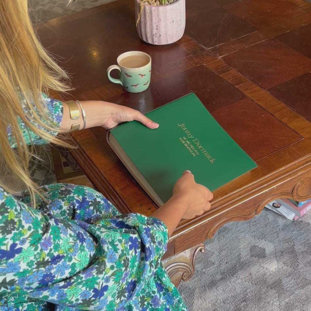 Load and play video in Gallery viewer, a girl picks up the condolence book, opens the first page of the condolence book and then puts it down again. The condolence book has been personalised with gold writing
