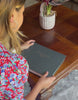 a woman looks through a large corporate leavers book. It is black with company details on the front. It is made by BeGolden