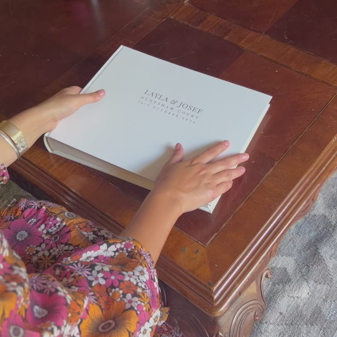 The video shows someone feeling her way through the wedding guest book, stroking the front and turning it over. it has been printed on the front with gold lettering.