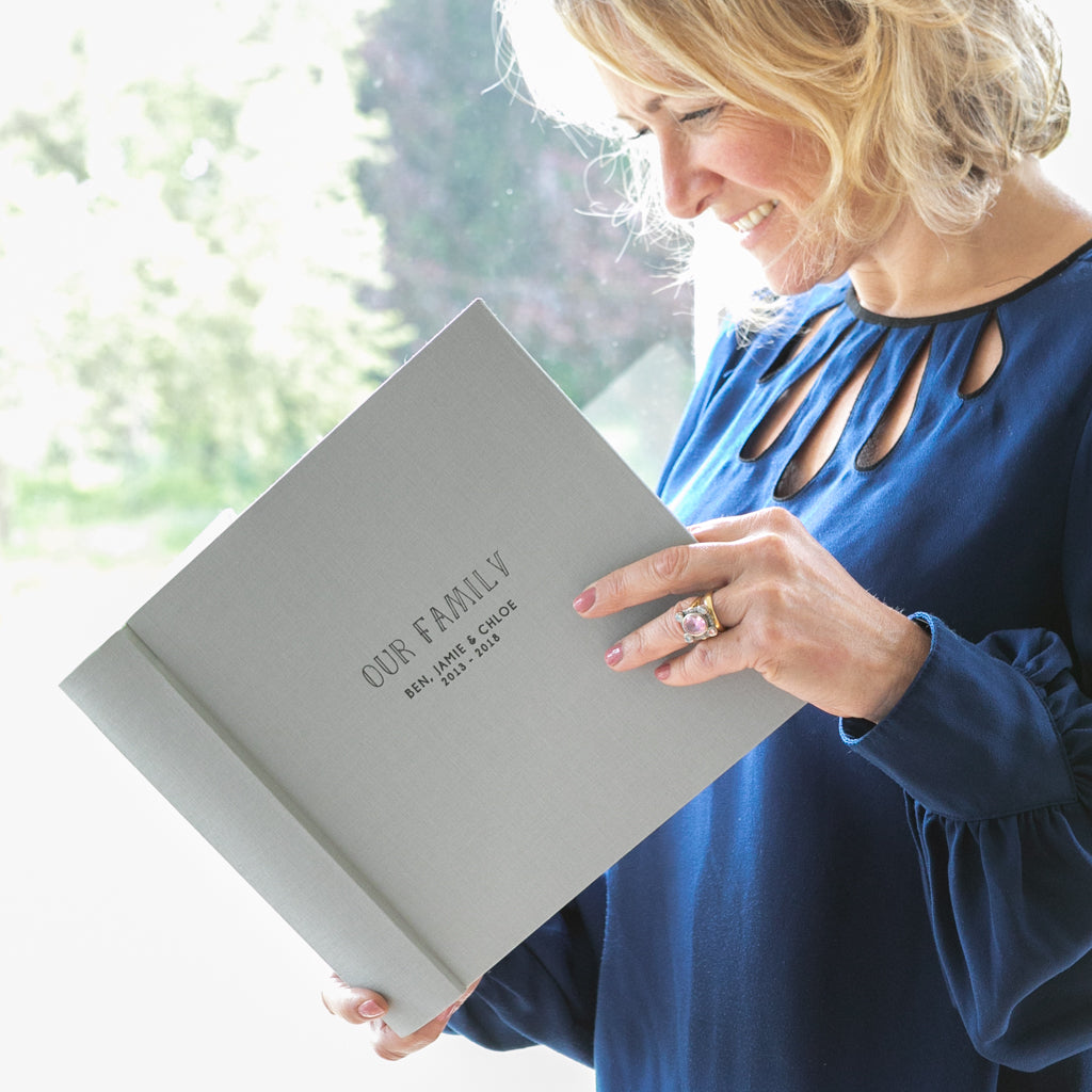 a lady smiling as she looks through a family photograph album