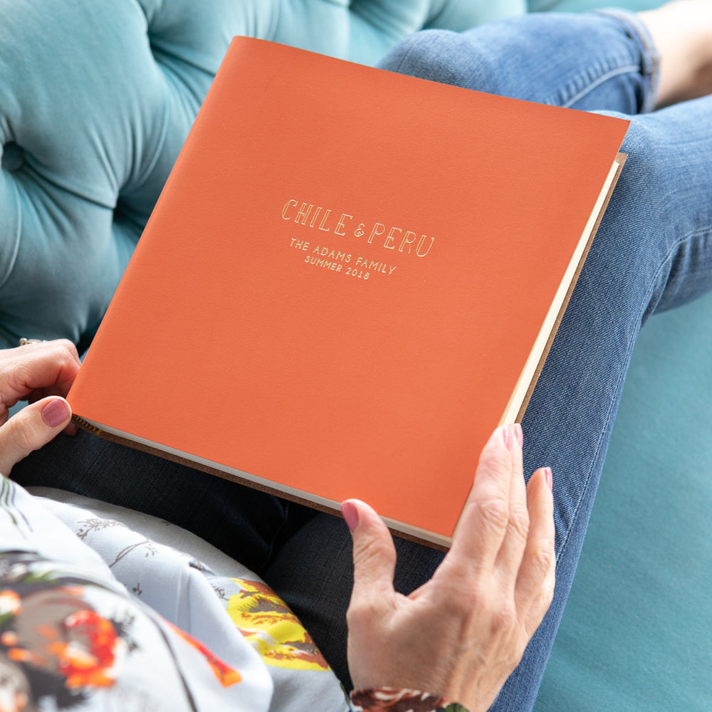 a lady about to look through an orange family travel album