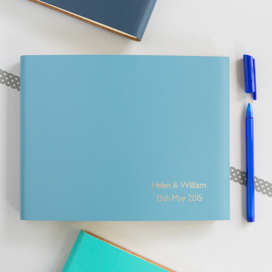 a blue leather guest book which has been personalised with two names and a date
