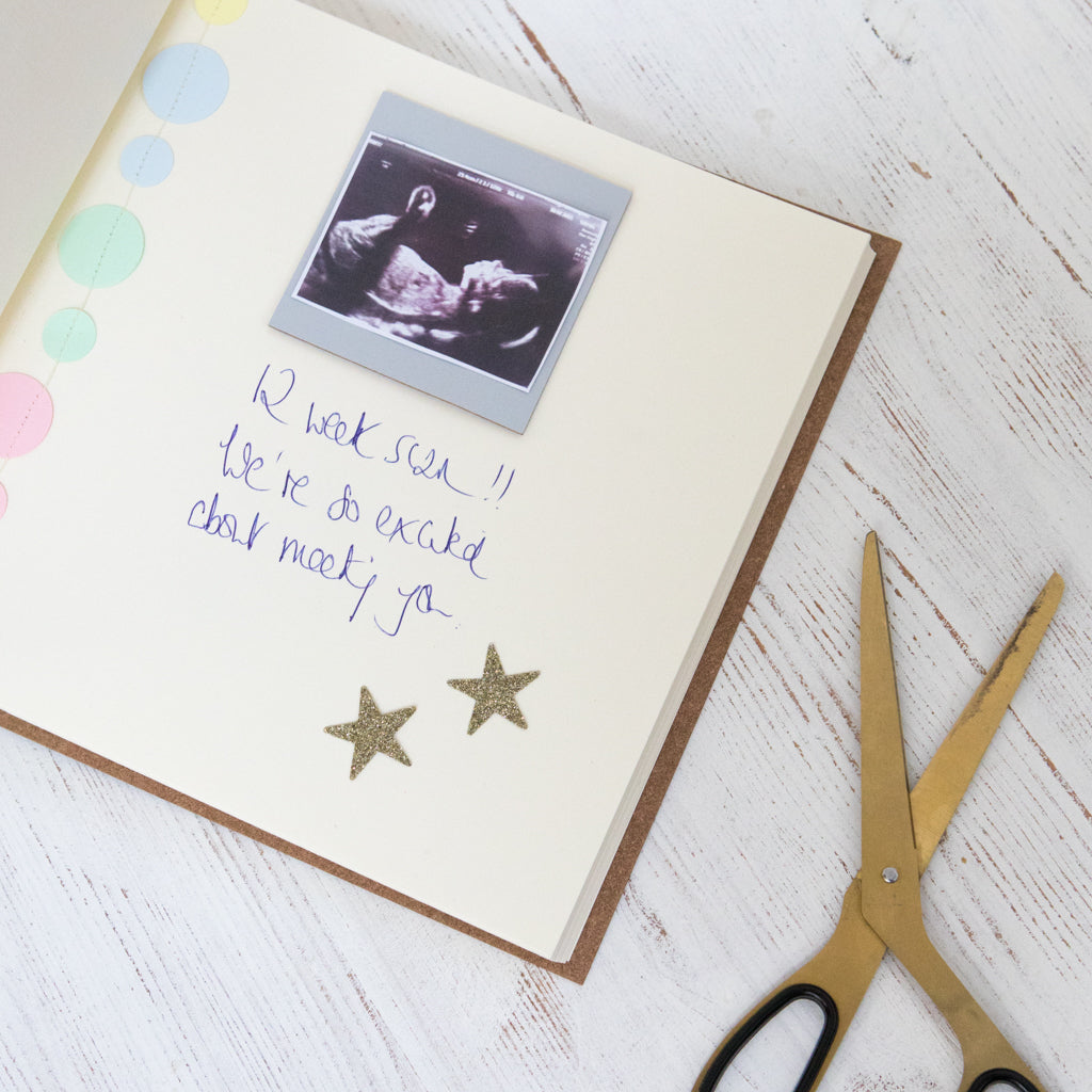 Load image into Gallery viewer, inside of the baby shower photo album and you can see a picture of a scan of the baby, a message and two gold stars
