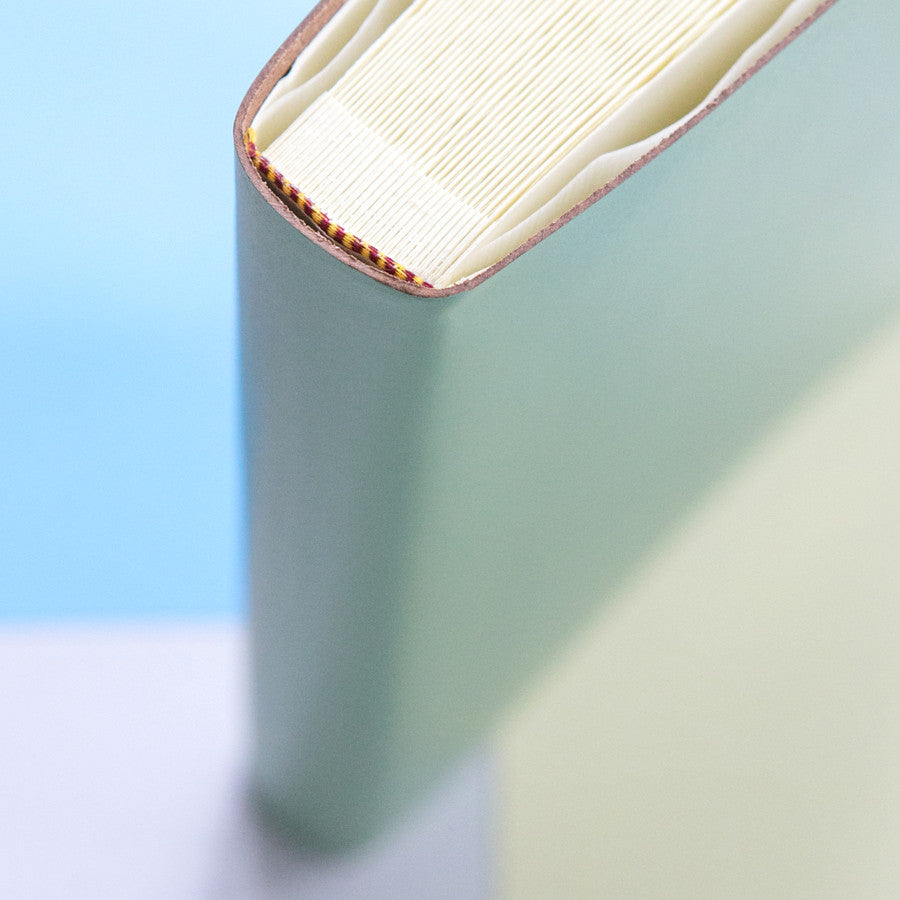 a close up of an a4 leather photo album showing the pages, the glassine interleaves and the headband. It shows the traditional binding