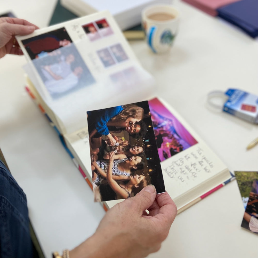 
                      
                        A lady sitting at a desk putting party photographs into an album
                      
                    