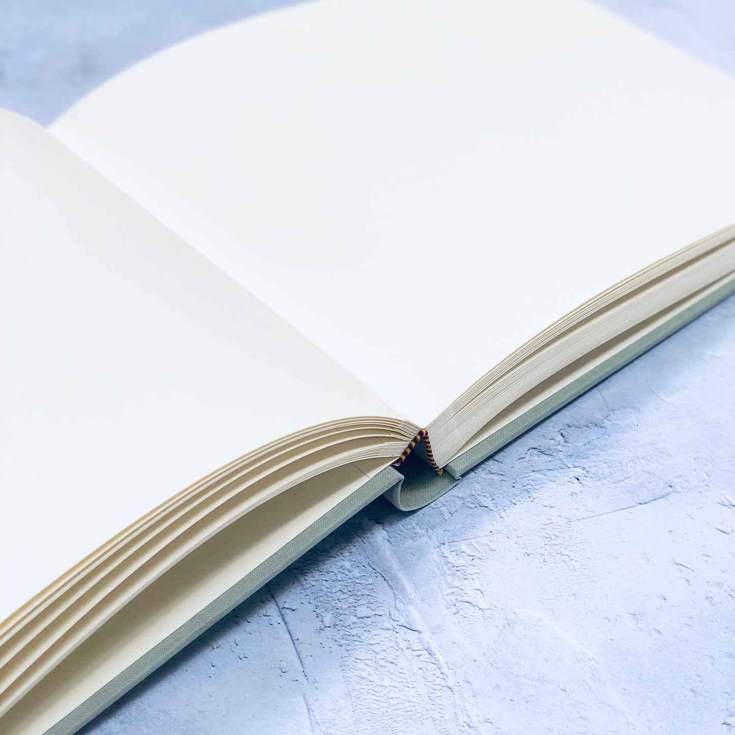 a large linen wedding guest book lies open on the table and you can see the blank pages 