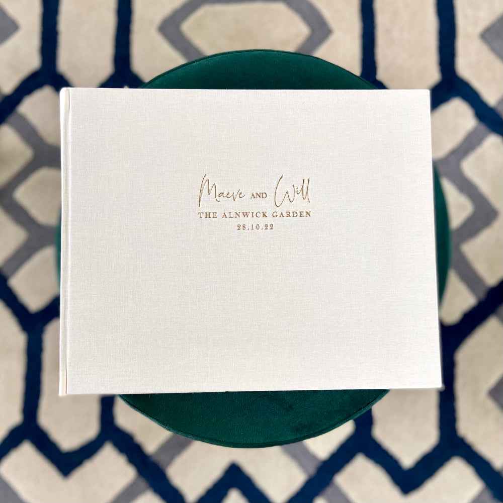 A beautiful ivory wedding album resting on a green table 