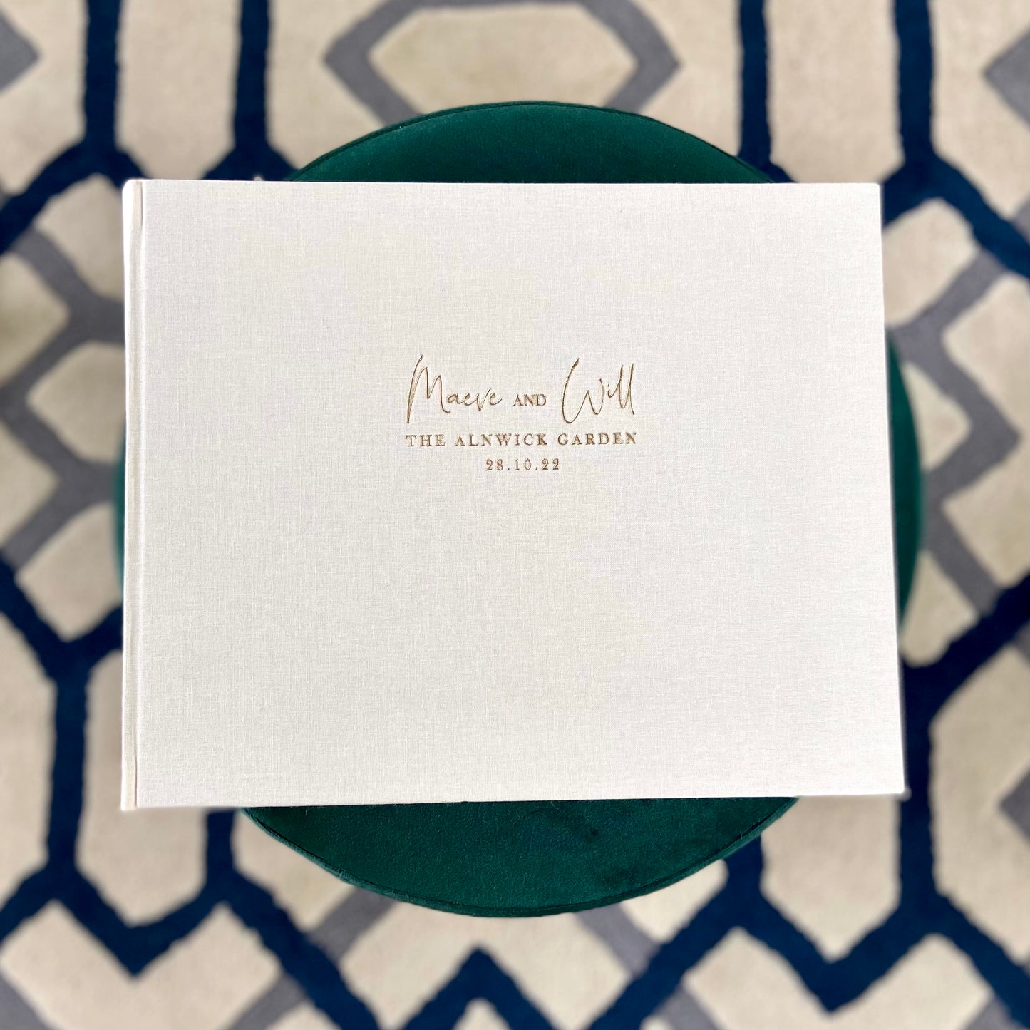 A beautiful ivory wedding album resting on a green table 