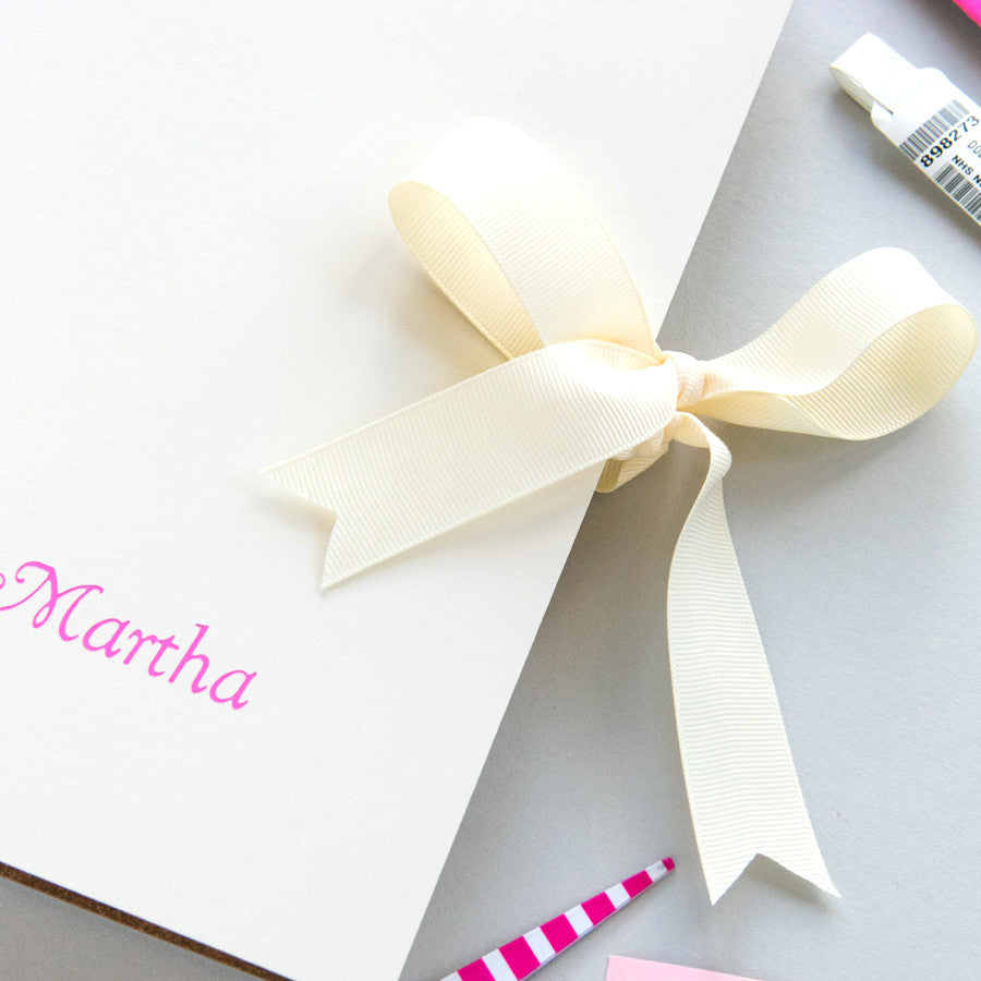 Load image into Gallery viewer, a close up photo of the leather baby album shows the ivory ribbon in a bow and the pink writing of the name Martha
