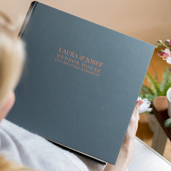 Load image into Gallery viewer, a woman is holding a large black photo album in her hands and you can see that it has been printed on the front with wedding details 
