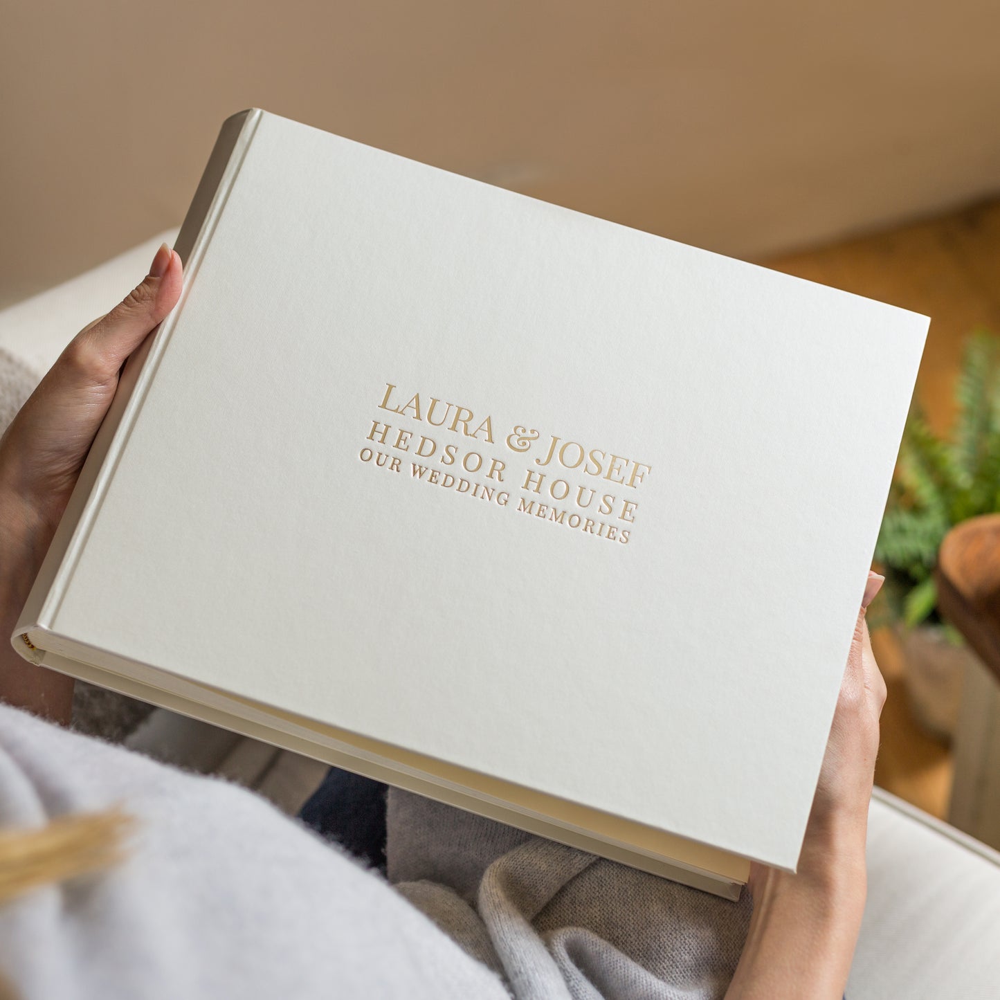 a woman holds her wedding guest book in her hands - it has been personalised with wedding details on the front
