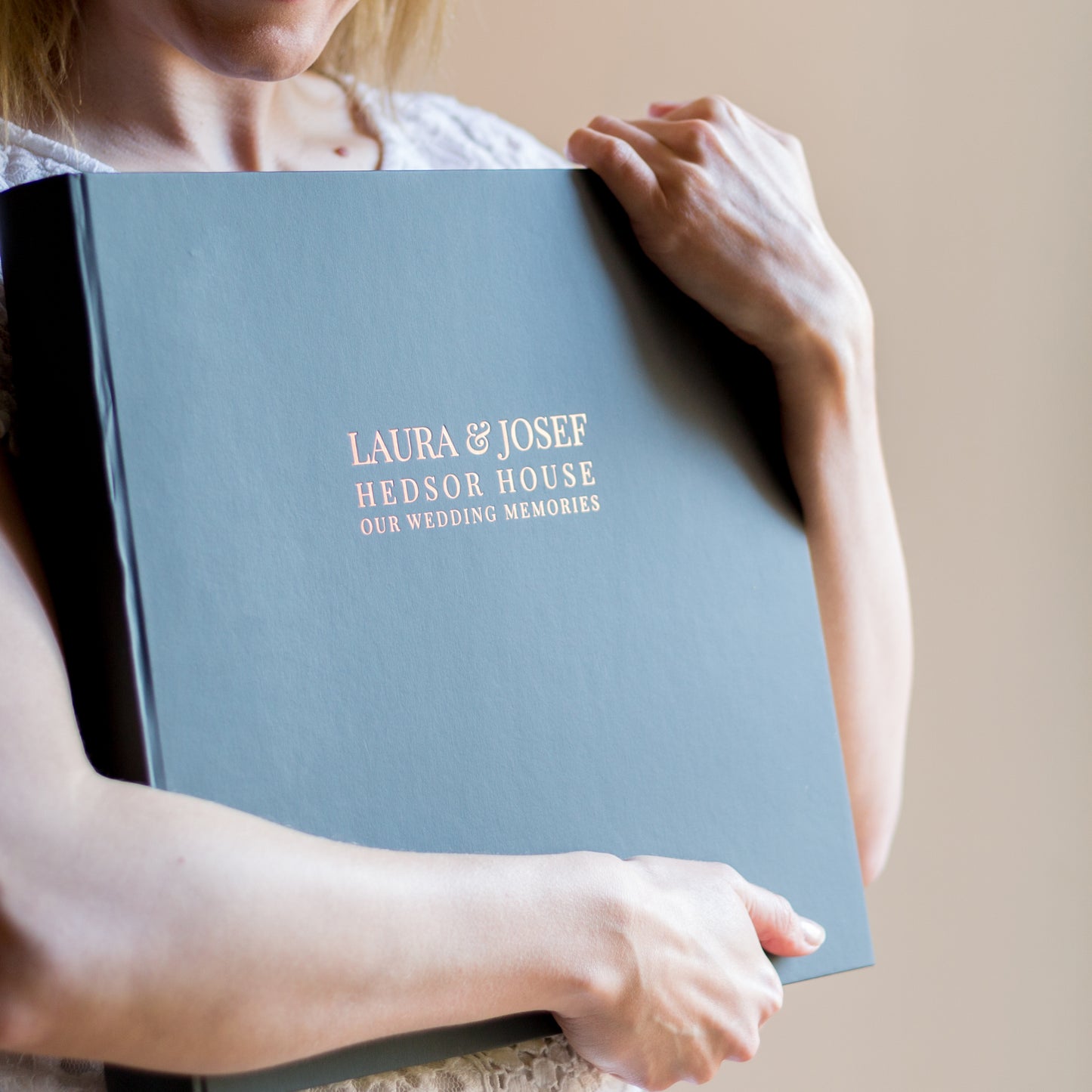 Load image into Gallery viewer, a woman is clutching a large personalised photo album in her arms. The photo album has been printed on the front with the date of the wedding, the weddign venue and the names of the bride and groom
