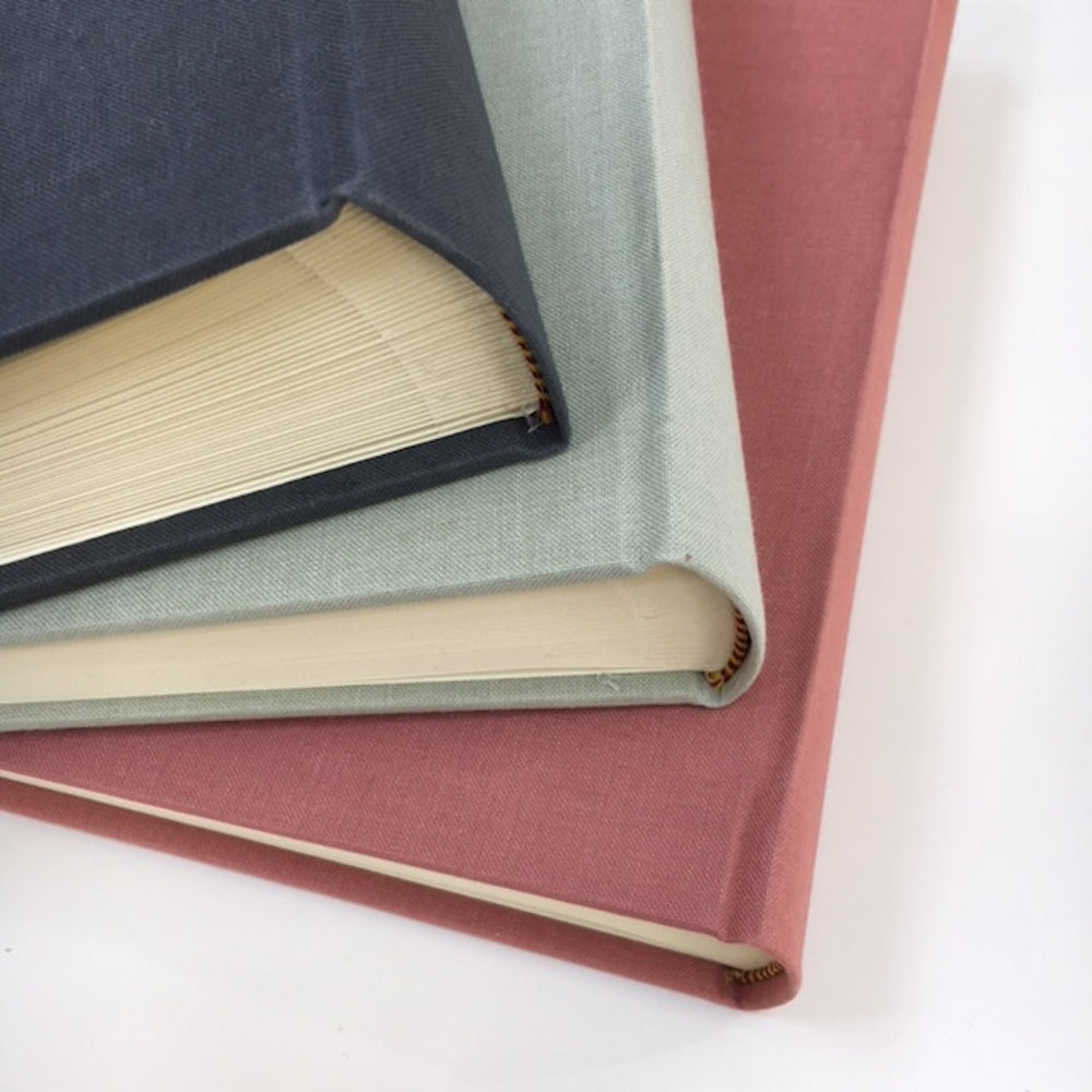 
                      
                        There are three linen books on top of one another fanned out. There are three different colours on show.
                      
                    